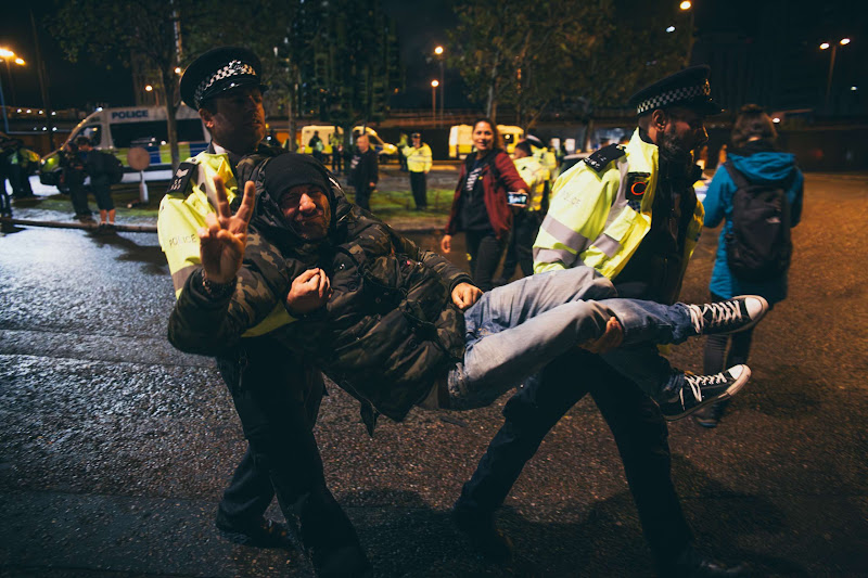 Activist Arrested By Police Does The Peace Sign At Fish Market Protest